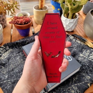 May include: A red coffin-shaped bookmark with the text "I have crossed oceans of time to find you." and the words "Dracula Bram Stoker" at the bottom. Two bats are cut out of the bookmark.