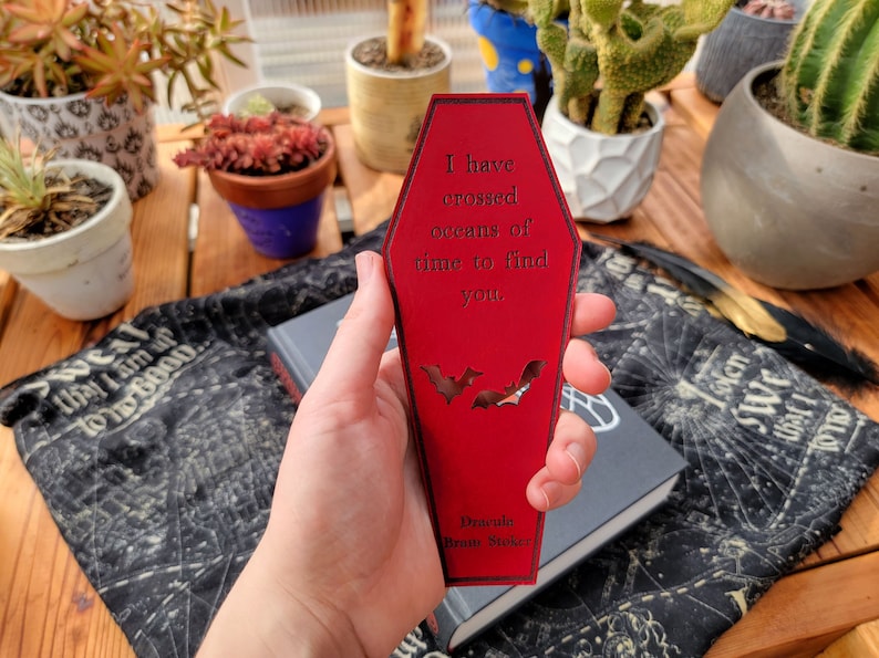 May include: A red coffin-shaped bookmark with the text "I have crossed oceans of time to find you." and the words "Dracula Bram Stoker" at the bottom. Two bats are cut out of the bookmark.