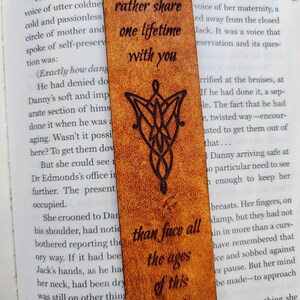 May include: A brown leather bookmark with a black design of the One Ring from the Lord of the Rings. The bookmark has the quote "Rather share one lifetime with you than face all the ages of this" inscribed on it.