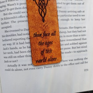 May include: A brown leather bookmark with a quote from the Lord of the Rings: "than face all the ages of this world alone."