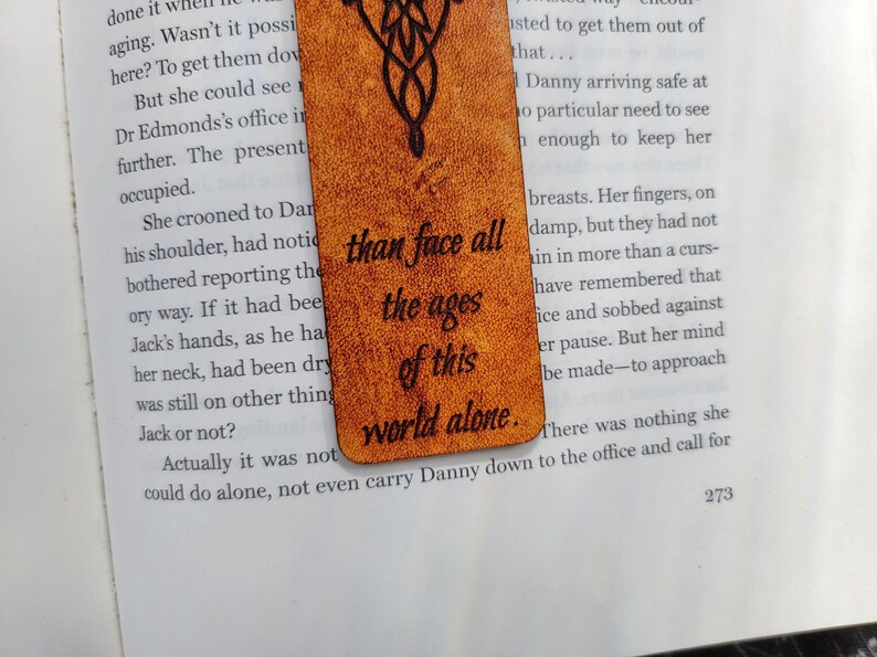 May include: A brown leather bookmark with a quote from the Lord of the Rings: "than face all the ages of this world alone."