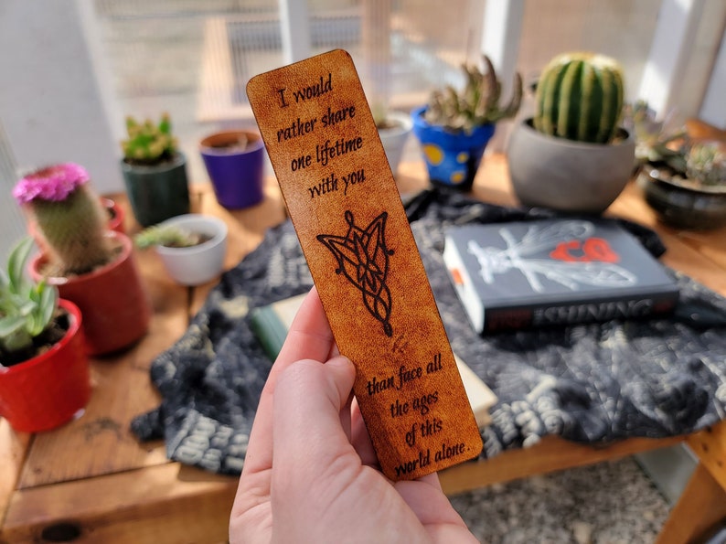 May include: A brown leather bookmark with a quote from the Lord of the Rings: "I would rather share one lifetime with you than face all the ages of this world alone." The bookmark features a design of the One Ring.