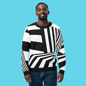 K&ouml;nnte beinhalten: Ein schwarz-wei&szlig; gemusterter Pullover. Der Pullover hat ein auff&auml;lliges Design aus Streifen und Formen in Schwarz und Wei&szlig;. Der Pullover wird von einer Person mit dunklem Haar und Bart getragen, die eine blaue Jeans tr&auml;gt.