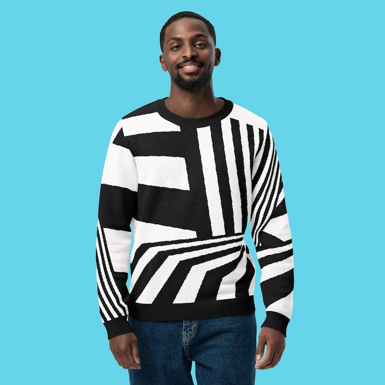 K&ouml;nnte beinhalten: Ein schwarz-wei&szlig; gemusterter Pullover. Der Pullover hat ein auff&auml;lliges Design aus Streifen und Formen in Schwarz und Wei&szlig;. Der Pullover wird von einer Person mit dunklem Haar und Bart getragen, die eine blaue Jeans tr&auml;gt.