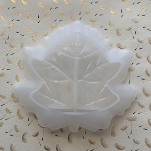 May include: A white silicone mold shaped like a maple leaf. The mold has a detailed vein pattern and is designed for crafting.