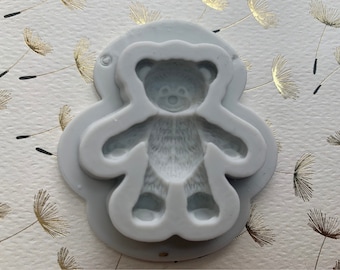 May include: A gray silicone mold shaped like a teddy bear. The mold is designed to create a detailed teddy bear shape.