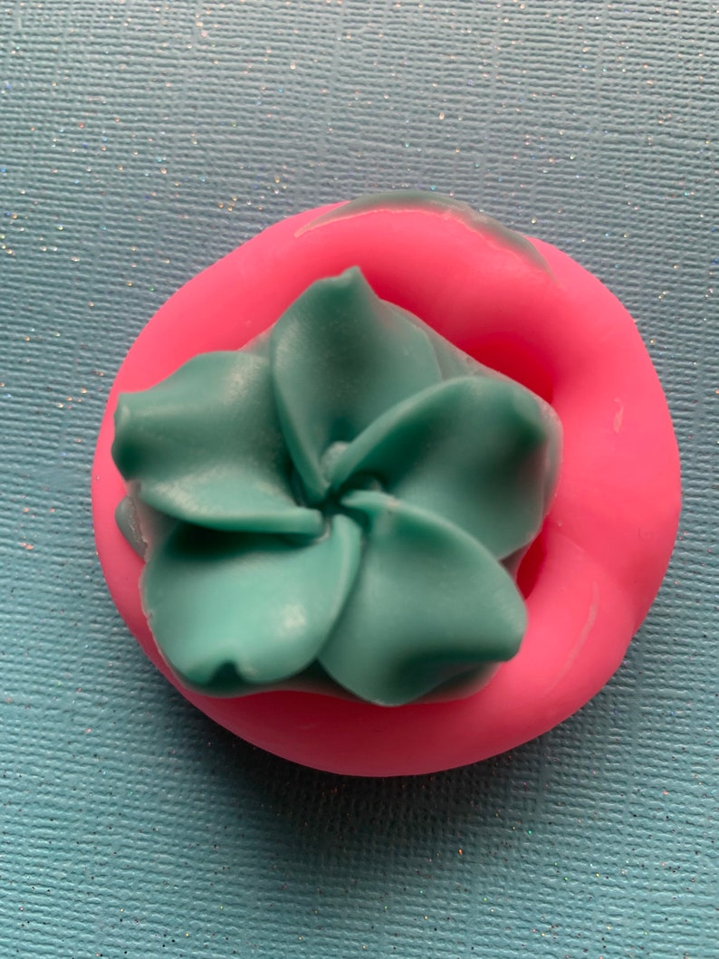 May include: A teal blue flower shaped silicone mold in a pink silicone mold.