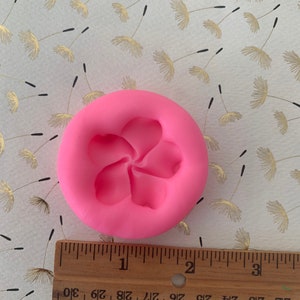 May include: Pink silicone mold with a single five-petal flower design. The mold is approximately 2 inches in diameter.