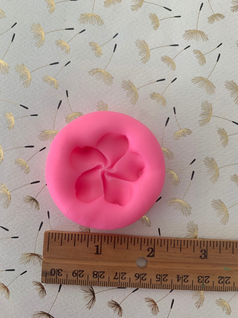 May include: Pink silicone mold with a single five-petal flower design. The mold is approximately 2 inches in diameter.