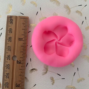 May include: Pink silicone mold with a five-petal flower design. The mold is approximately 2 inches in diameter.