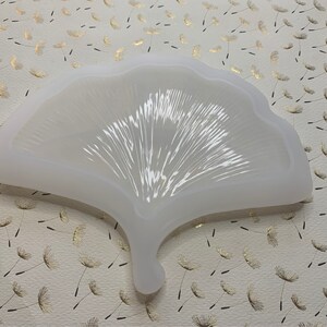 May include: White silicone mold shaped like a ginkgo leaf. The mold has a detailed, textured surface.