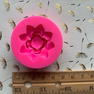 May include: Pink silicone mold for making a flower-shaped cake decoration. The mold is about 2 inches in diameter.