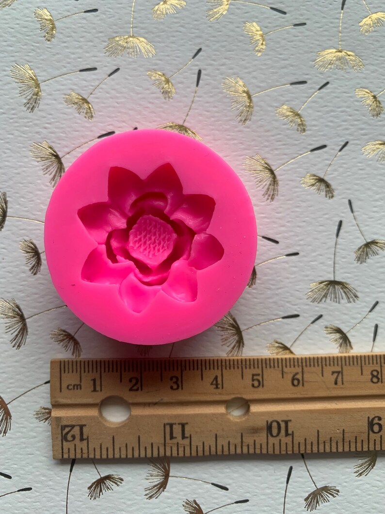 May include: Pink silicone mold for making a flower-shaped cake decoration. The mold is about 2 inches in diameter.