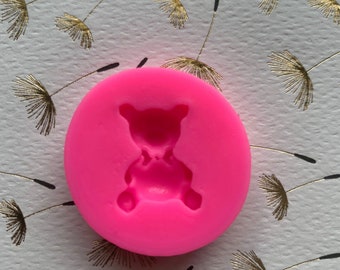 May include: Pink silicone mold with a teddy bear design. The mold is round and has a smooth surface.