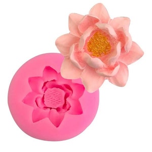 May include: Pink silicone mold for making a flower cake decoration. The mold has a detailed design of a flower with multiple petals. A pink flower is shown next to the mold.