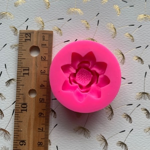 May include: Pink silicone mold with a single cavity shaped like a flower. The flower has five petals and a center with a raised design.