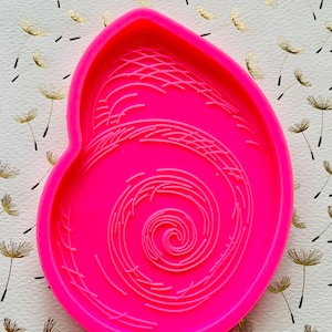 May include: Pink silicone mold with a swirl design. The mold is shaped like a heart.