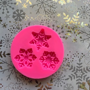 May include: Pink silicone mold with three snowflake designs. The mold is for making edible decorations.