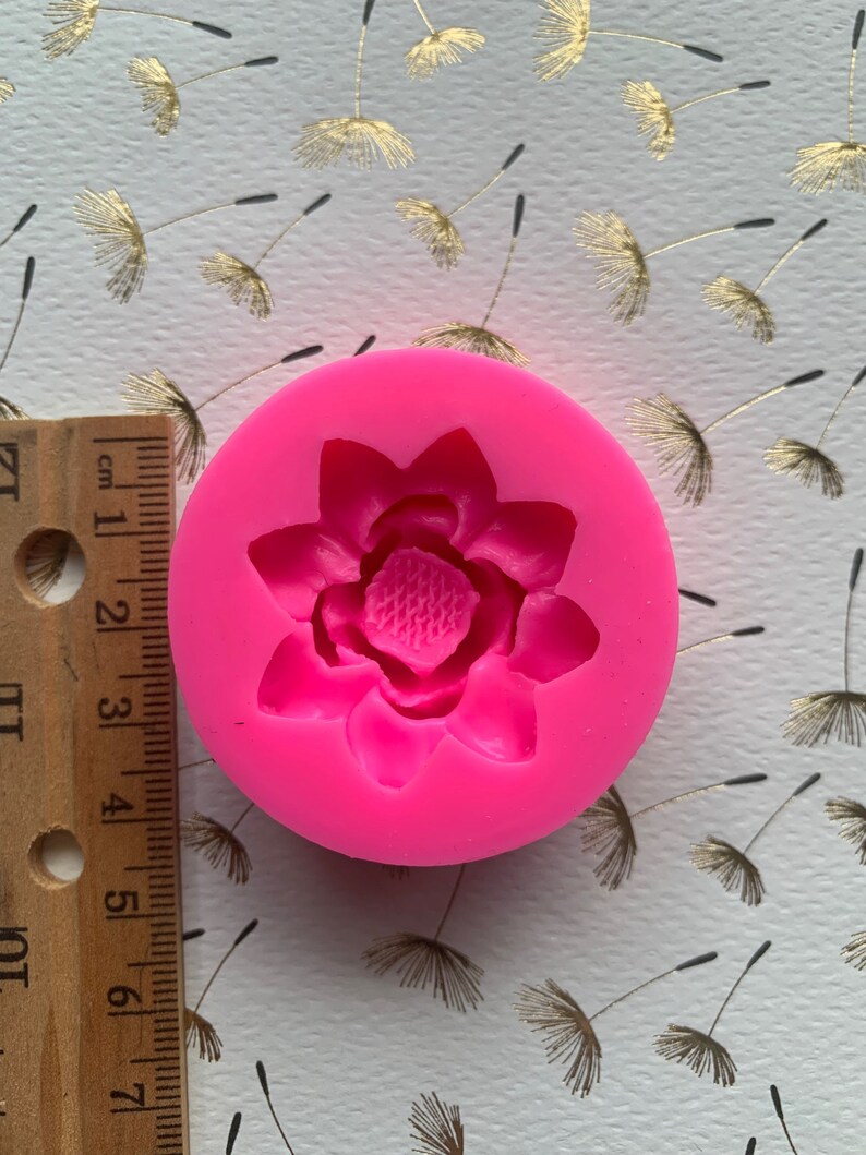 May include: Pink silicone mold with a single flower design. The mold is approximately 2 inches in diameter.