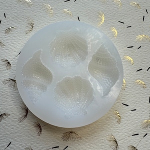 May include: White silicone mold with three round cavities, each with a textured design resembling a flower.