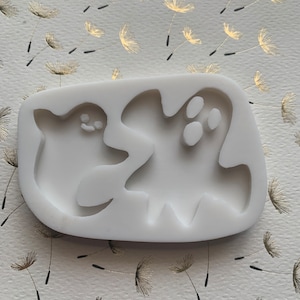 May include: White silicone mold with two ghost shapes. The mold is designed for making edible treats like candy or fondant.