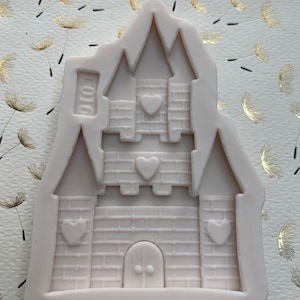 May include: A white silicone mold shaped like a castle with a brick pattern and four heart-shaped cutouts. The mold has the number "2016" embossed on the side.