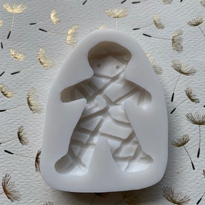May include: White silicone mold for making a gingerbread man cookie. The mold features a detailed design of a gingerbread man with a cracked icing pattern.