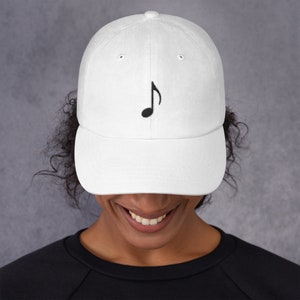 May include: A white baseball cap with a black embroidered musical eighth note on the front. The cap has a curved brim and a classic six-panel design. The hat is made of a soft, durable fabric.