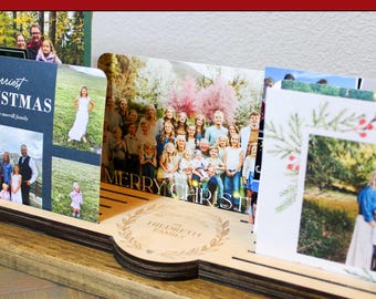 Può includere: Un portacarte natalizio in legno che mostra diverse cartoline di Natale. Il supporto ha un design personalizzato con il testo "PERSONALIZED HOLIDAY CARD HOLDER" e "CUSTOM | ALL WOOD | EASY TO USE". Le cartoline presentano foto di famiglia e le parole "MERRY CHRISTMAS".