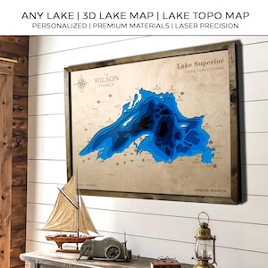 May include: A wooden 3D lake map of Lake Superior, framed in a dark wood. The map shows the lake's topography in shades of blue, with the text "Lake Superior" and "The Wilson Family". The text at the top reads "ANY LAKE | 3D LAKE MAP | LAKE TOPO MAP".