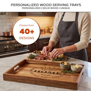 May include: A rectangular wooden serving tray with cutout handles, featuring the engraved text "BLESS this HOME AND ALL WHO ENTER" in a circular design. The tray is made of natural wood with visible grain and sits on a marble surface.