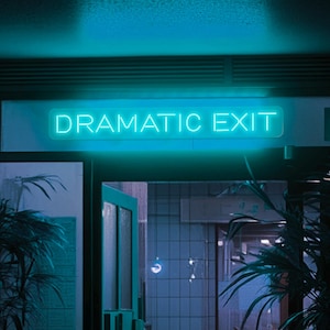 May include: A teal neon sign above a doorway reads "DRAMATIC EXIT." The sign is illuminated against a dark background, with a hint of a building interior visible through the open door. The overall aesthetic is moody and atmospheric.