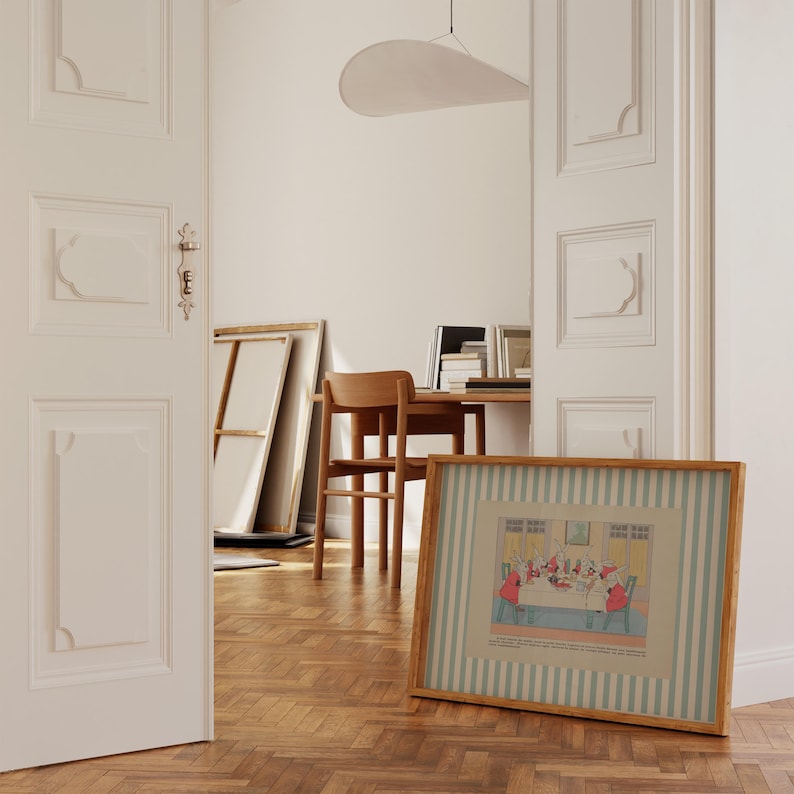 May include: A framed illustration with a light wood frame and a striped border in shades of blue and white. The illustration depicts a gathering of figures around a table. The scene is set in a room with a wooden floor and white walls.
