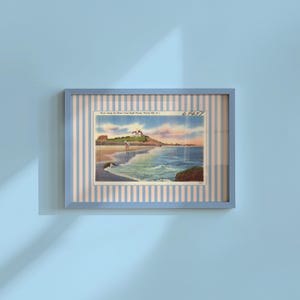 Può includere: Una cartolina vintage incorniciata con una scena costiera con un faro, una spiaggia e l'oceano. La cartolina è inserita in una cornice blu con uno sfondo a righe. Il testo sulla cartolina recita "View along the Shore from Light House, Watch Hill, R.I."