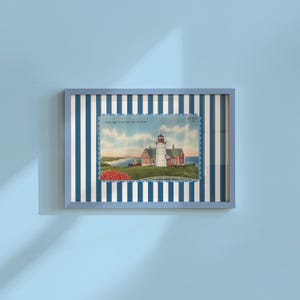 Puede incluir: Impresión enmarcada con una imagen de postal vintage de un faro con techo rojo y torre blanca. El marco es azul claro y el fondo tiene rayas verticales azules y blancas. La imagen de la postal incluye texto.