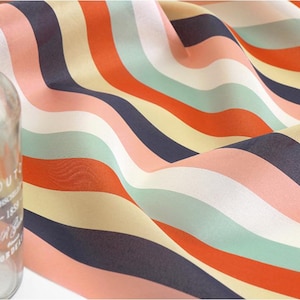May include: A colorful striped fabric with wavy lines in shades of orange, pink, cream, blue, and green. The fabric is made of a lightweight, sheer material.