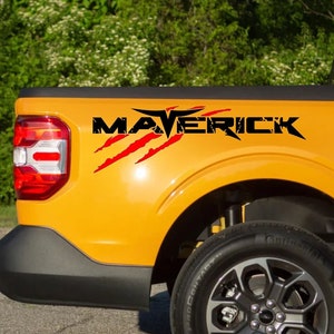 May include: A yellow Ford Maverick pickup truck with a black and red "MAVERICK" decal on the side of the truck bed.