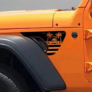 May include: Black graphic decal featuring a sunset scene with palm trees and a beach design. The decal is placed on the side of an orange vehicle, near the front tire. The vehicle's body is orange and black.