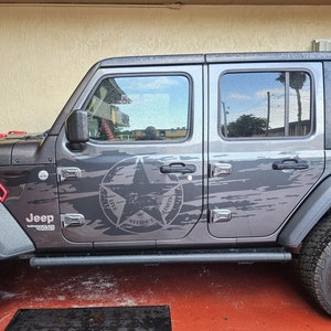 May include: A gray Jeep Wrangler with a black and white camouflage design and a star with the words "Live Without Limits" on the side.