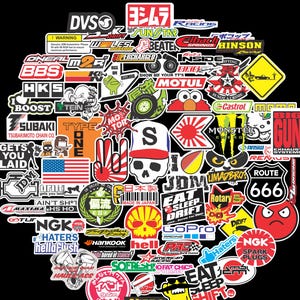 May include: A collection of colorful stickers with various logos and graphics. Includes the American flag, a skull with a hat, and text such as "Route 666", "Monster", and "Eat Sleep Drift".