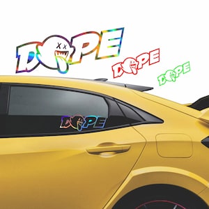 May include: A yellow car with a rainbow iridescent sticker on the back window that says "DOPE" with a cartoon ghost with an "X" on its eyes and a tongue sticking out.