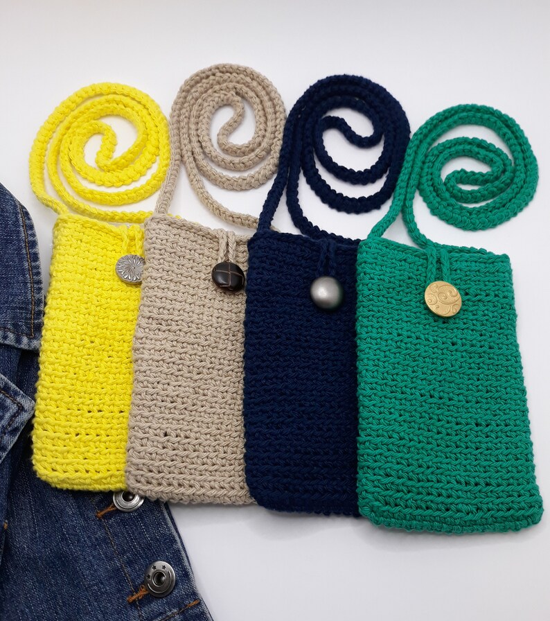 Crossbody phone bag has subtle raised close even stitches detailing each row. Feel soft and smooth. Top edging has a crochet button loop closure that loops around a 1 inch showy button sewn 1.5 inch from top edge. Same color strap display above bag.