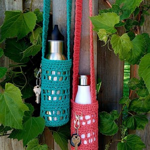 May include: Two crocheted water bottle holders with straps. One is teal and the other is coral. Both have keys attached to the straps.