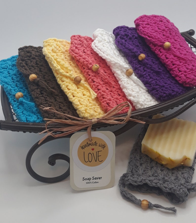 Soap Holder is a lacy feminine texture. Bags overlapped on black sleigh looking tray. Two crochet drawstrings same color as bag .5 inch from top of bag to cinch pouch shut. On end of each string a small wood bead. Handmade With Love sticker on bag.