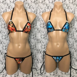 Puede incluir: Dos conjuntos de bikini negros con diferentes telas estampadas. Un conjunto tiene un estampado de llamas rojo, naranja y amarillo. El otro conjunto tiene un estampado azul y plateado. Ambos conjuntos tienen tirantes y lazos negros.