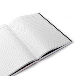 May include: An open notebook with lined pages and a black cover. The notebook is lying open on a white surface.