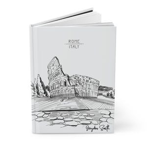 Peut inclure: Un carnet blanc avec une illustration en noir et blanc du Colis&eacute;e &agrave; Rome, en Italie. Le texte "ROME ITALIE" est imprim&eacute; sur la couverture. Le carnet est sign&eacute; "Jayden Smith".