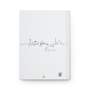 Peut inclure: Un carnet blanc avec un dessin au trait noir de l'horizon de Rome. L'horizon comprend le Colis&eacute;e, le Panth&eacute;on et la Fontaine de Trevi. Les mots "Rome" sont &eacute;crits sous l'horizon.