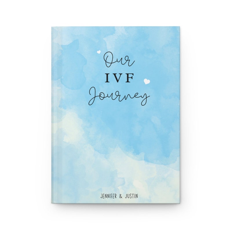 May include: A blue watercolor journal with the text "Our IVF Journey" and the names "Jennifer & Justin" at the bottom.