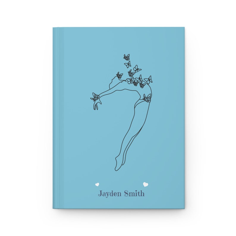 May include: A light blue hardcover journal featuring a black line art illustration of a person leaping with butterflies surrounding them. The name Jayden Smith is printed in dark gray text at the bottom, flanked by two small white heart icons.